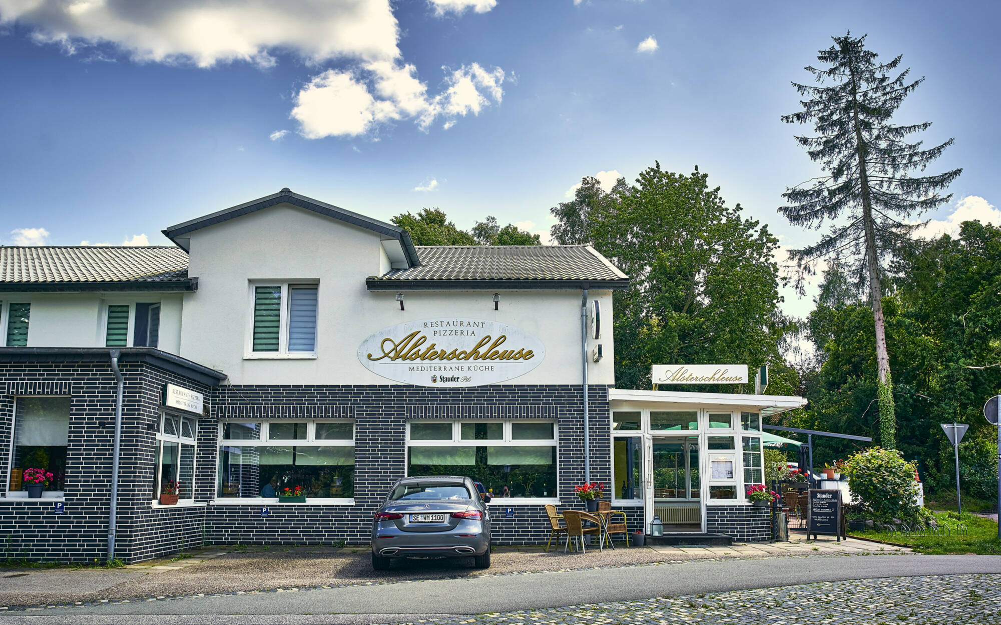Ristorante Alsterschleuse in Tangstedt – Außenansicht des Restaurants an der Alsterschleuse mit Schild und Terrasse